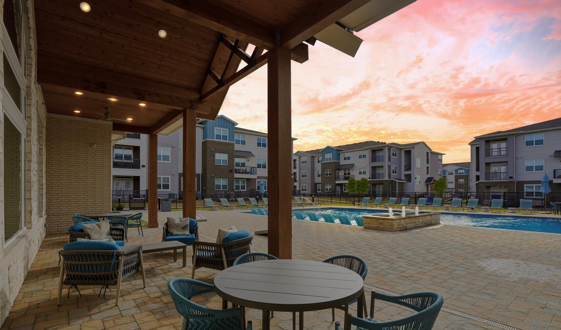 a patio with tables and chairs and a body of water in the background