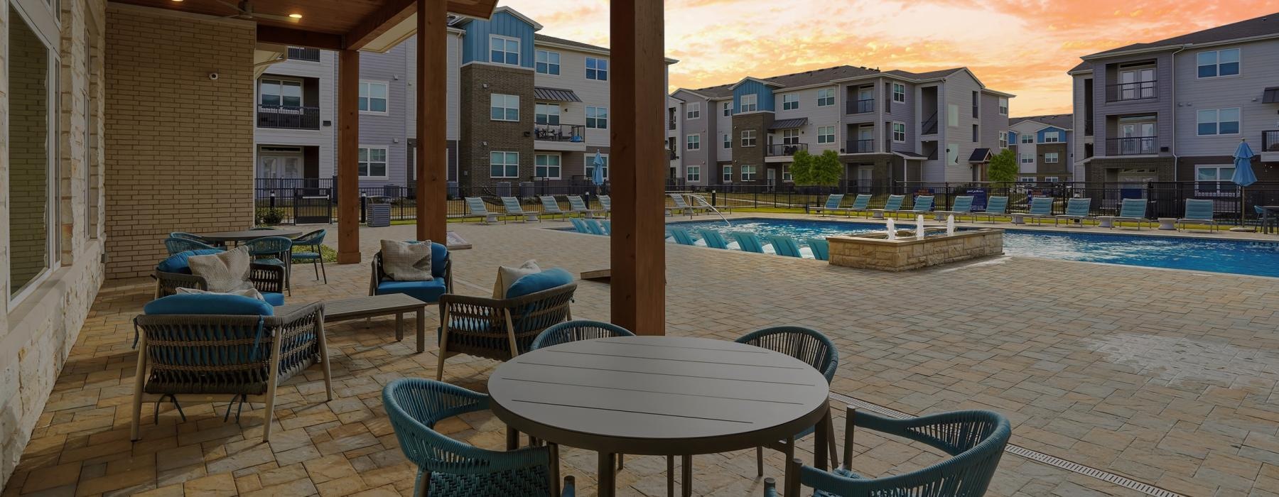 a patio with tables and chairs and a body of water in the background