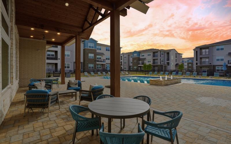 a patio with tables and chairs and a body of water in the background